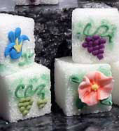 Decorated sugar cubes with purple and green grapes, orange and blue flowers